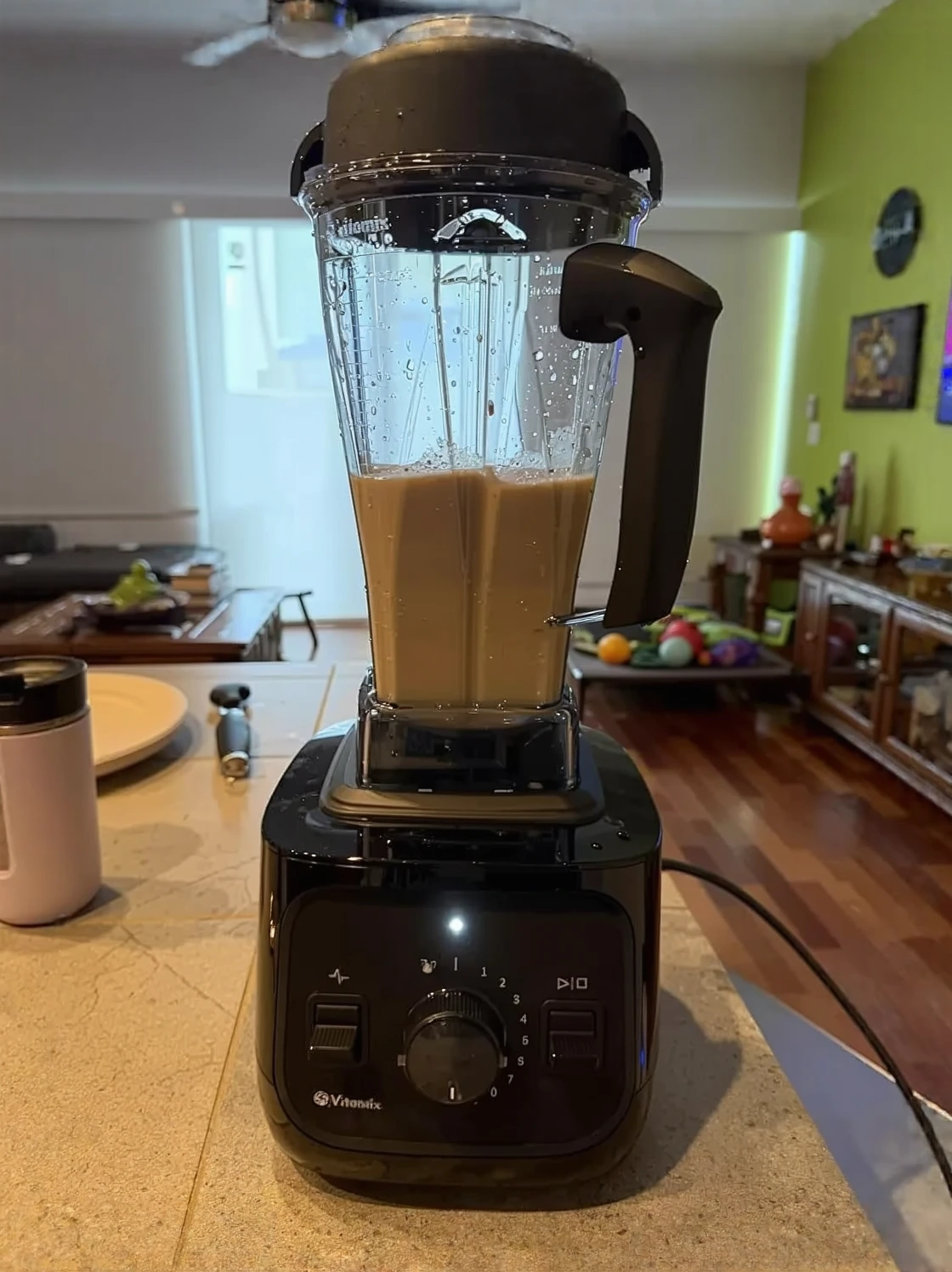 Customer photo of blended green smoothie in glass next to high-powered blender